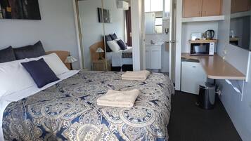 Una habitación de hotel con una cama grande, un escritorio, un microondas y una pequeña kitchenette.