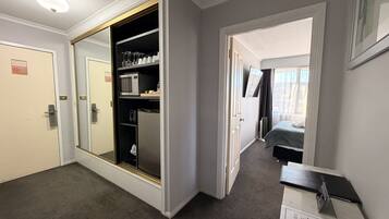 Habitación de hotel con vestidor, cama, escritorio con una laptop y vista al exterior.