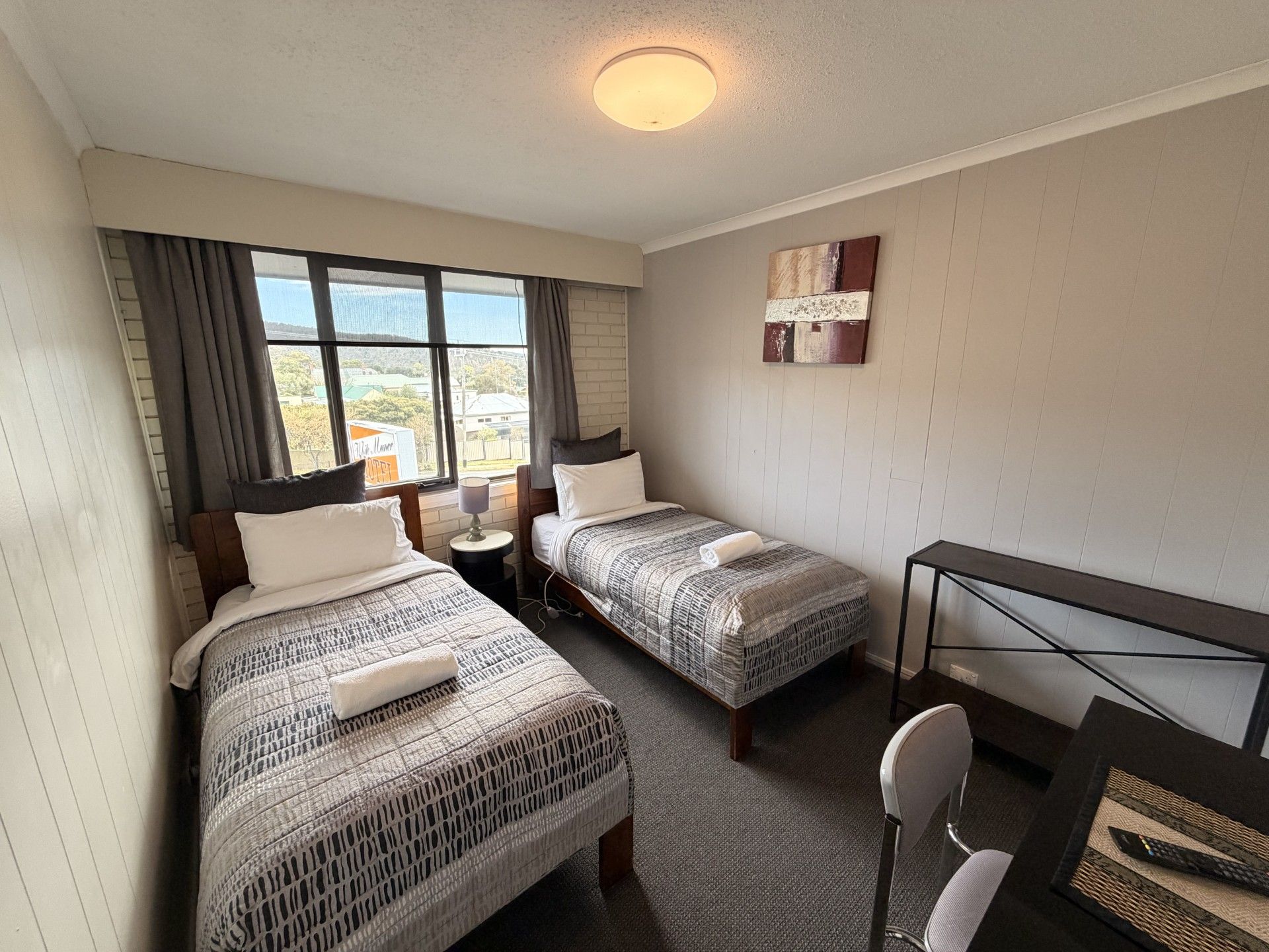 A hotel room with two beds, a desk, and a chair.