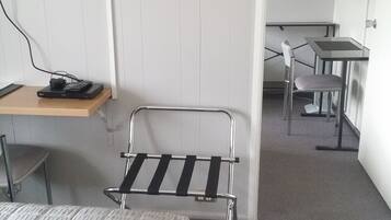 A hotel room with a bed, a desk with a computer, a TV mounted on the wall, and a chair.