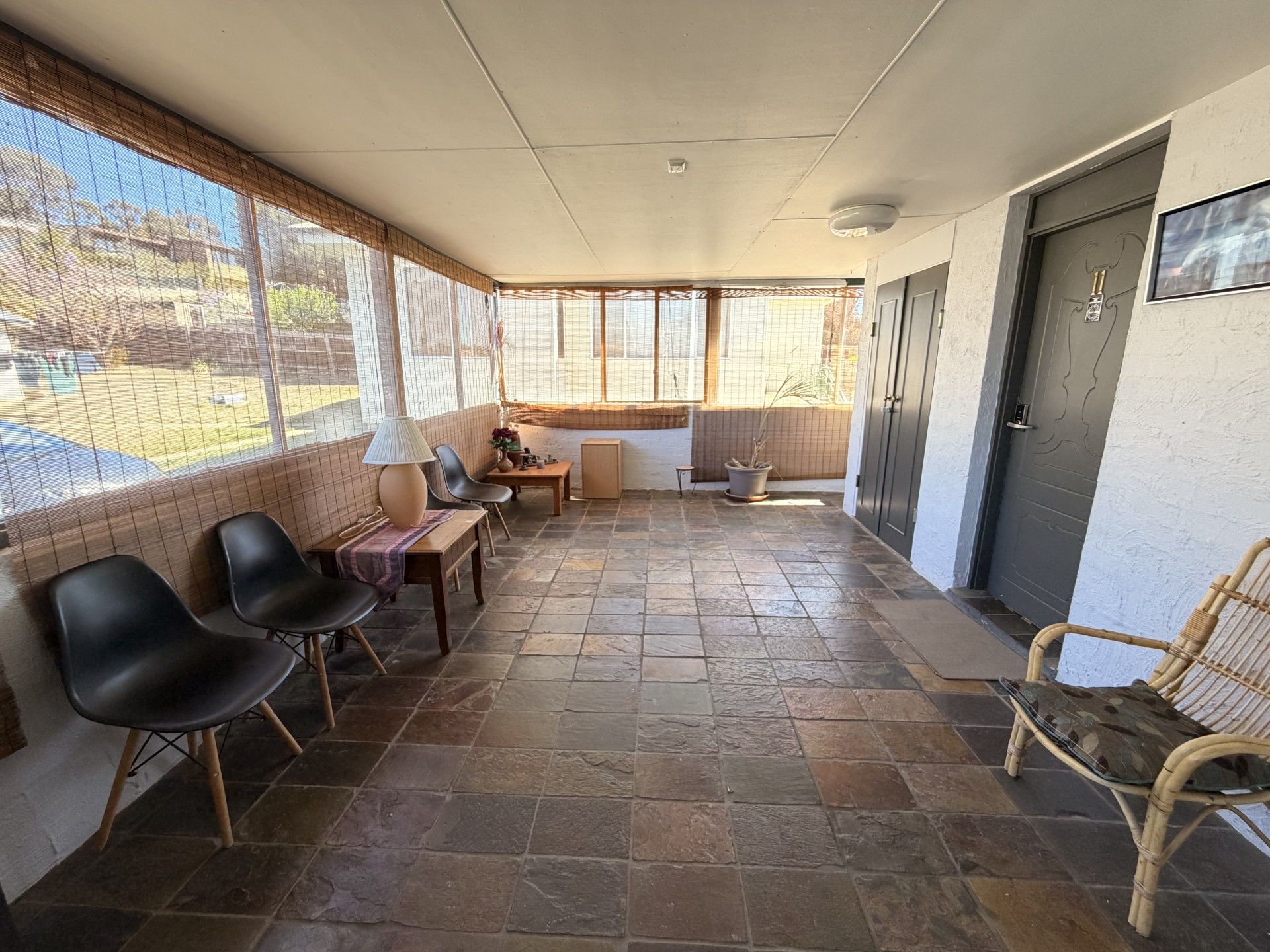 A covered patio area with stone flooring, seating, and a view of the outdoors.