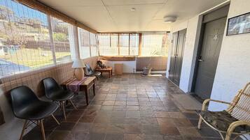 A covered patio area with stone flooring, seating, and a view of the outdoors.