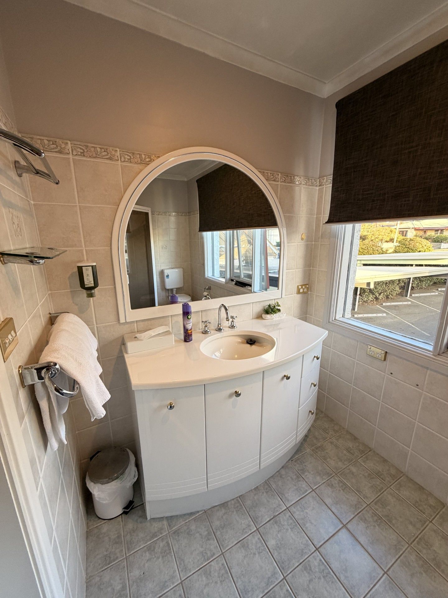 Un baño con un tocador blanco, un espejo grande y una ventana con vistas al exterior.