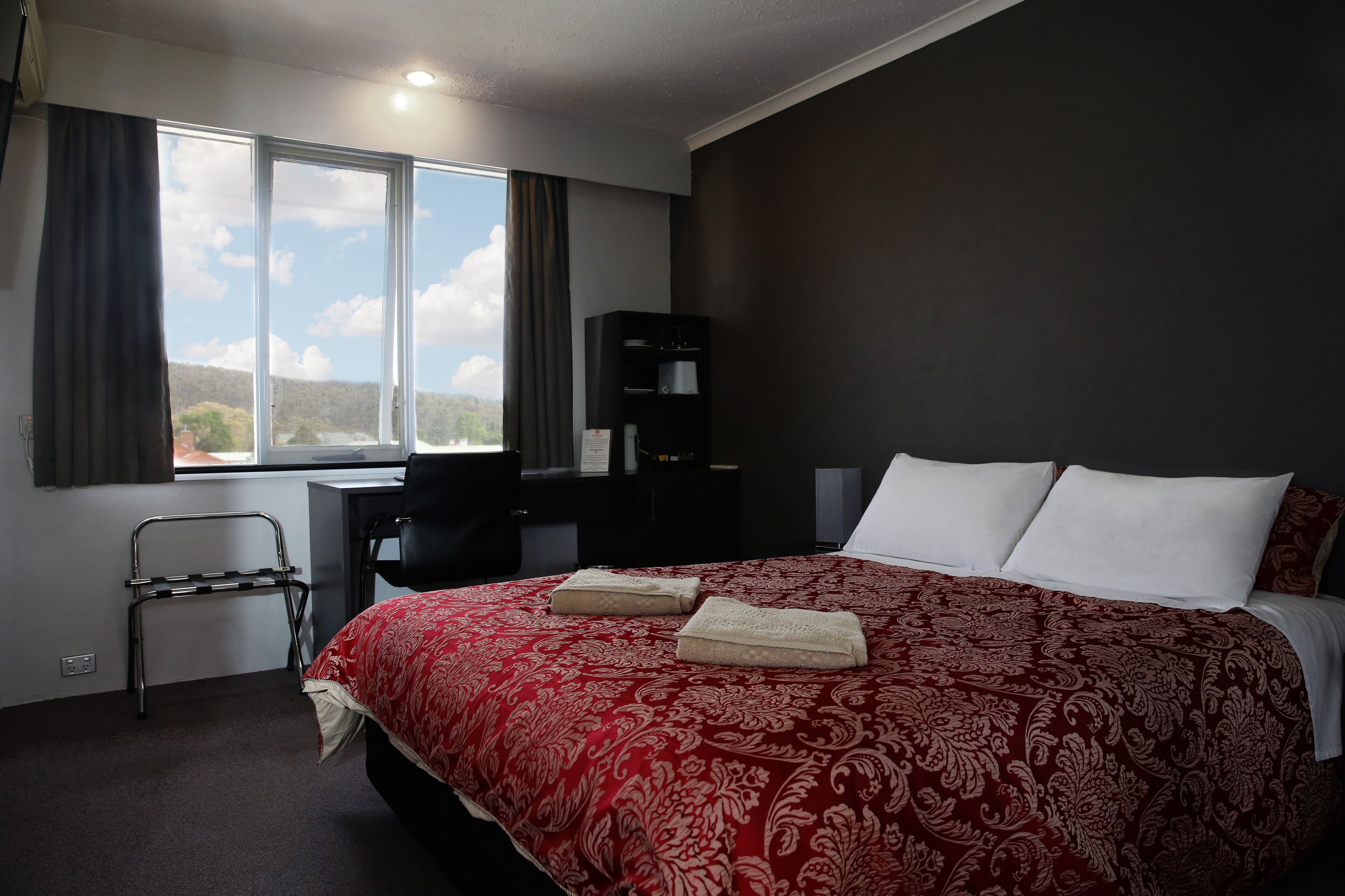 Une chambre d’hôtel avec un grand lit, un bureau et une vue sur l’extérieur.