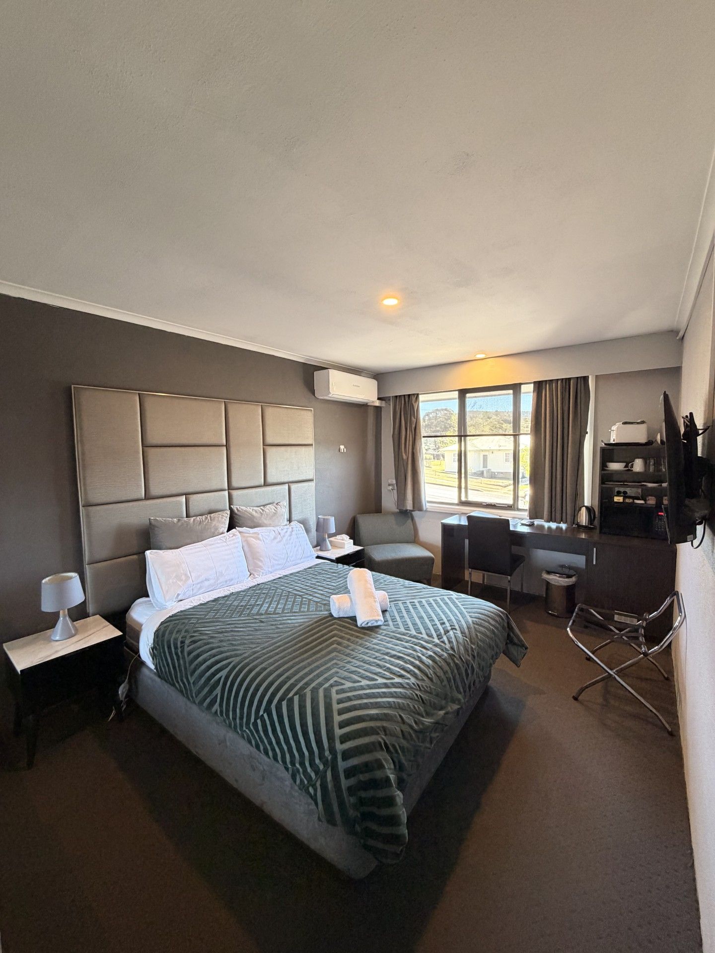 Een hotelkamer met een groot bed, een bureau, een stoel en uitzicht op het landschap.