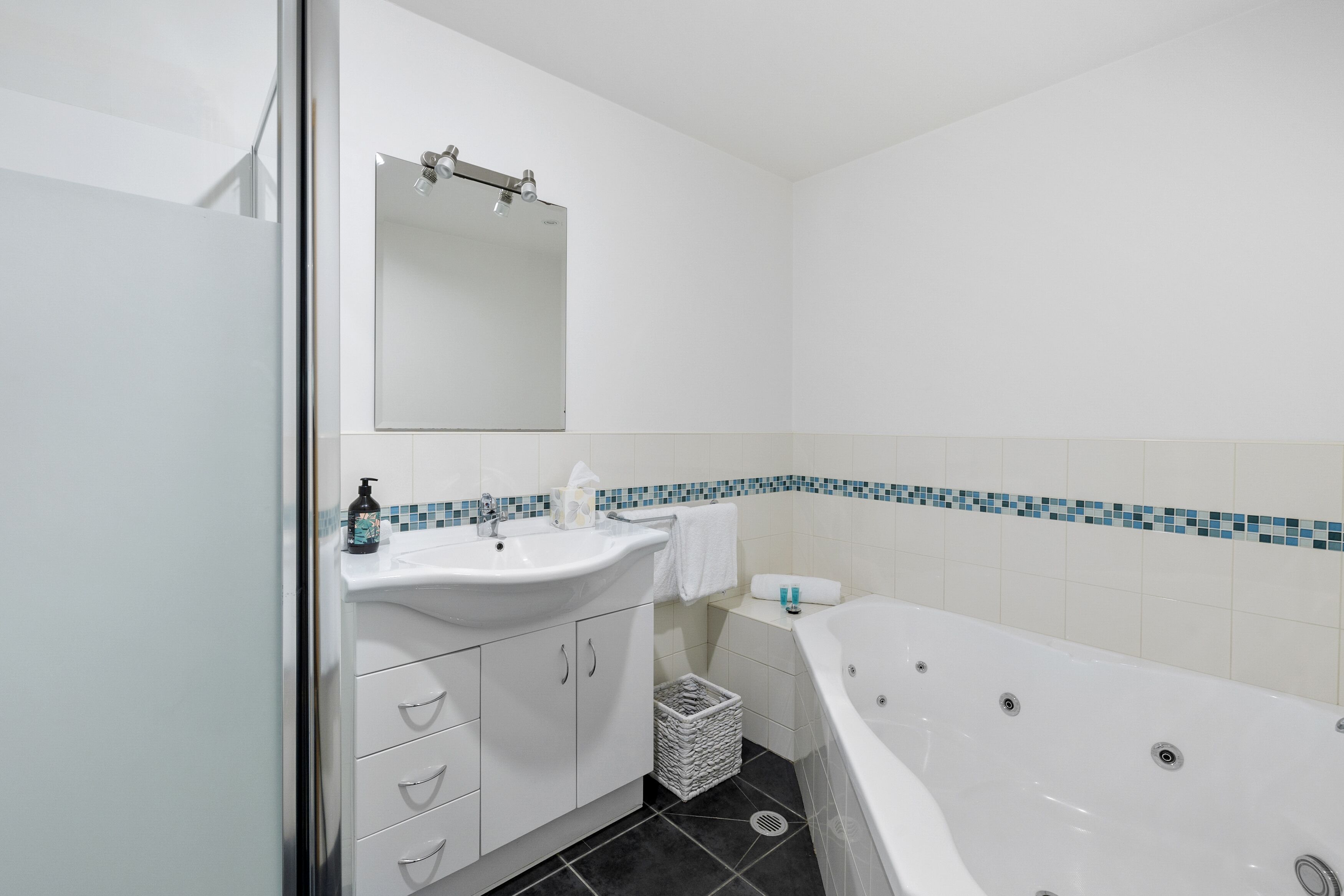 A modern bathroom with a white sink, mirror, and bathtub.