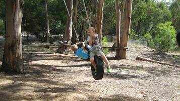 A person swinging on a tire swing in a wooded area.