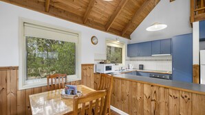 Una cocina con armarios de madera, una mesa de comedor con sillas y una ventana con vistas a zonas verdes.