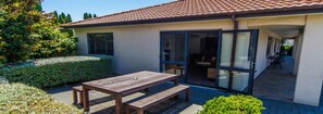 Uma casa moderna com um pátio, uma mesa de madeira e um banco.