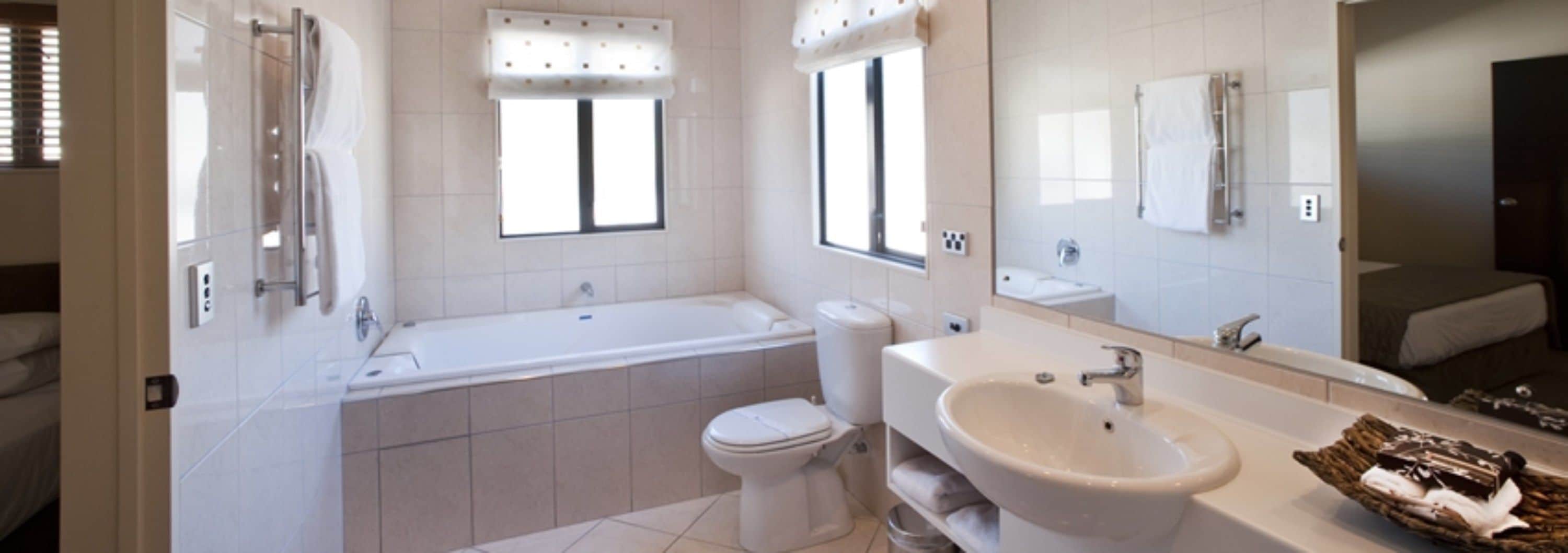 A modern bathroom with a bathtub, toilet, sink, and a large mirror.