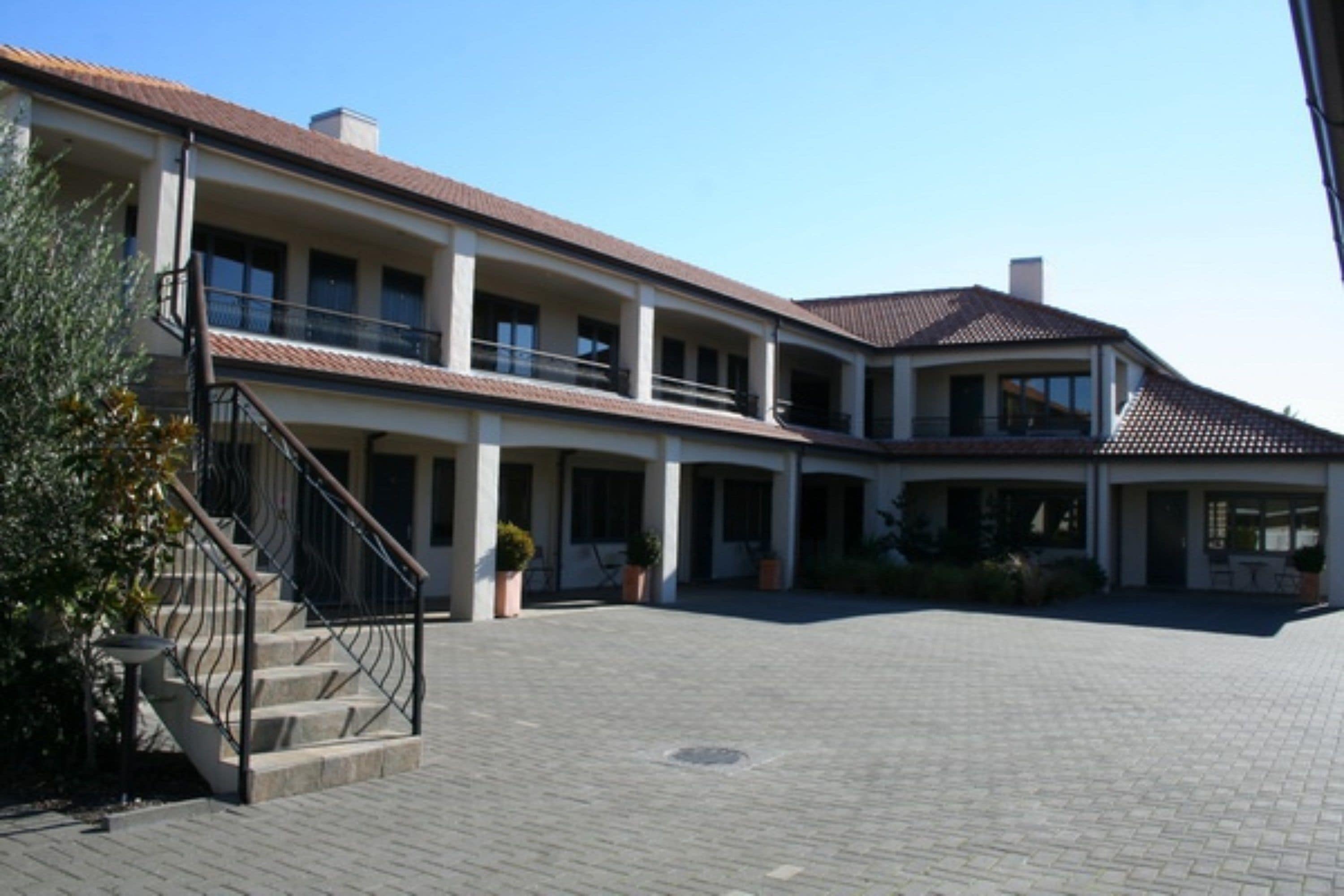 A two-story building with a central courtyard, multiple balconies, and a staircase leading to the upper floor.