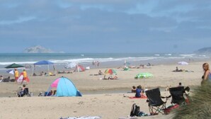 A beach with tents, umbrellas, and people. - Harvest Lodge (Havelock North)