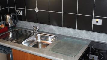 Una cocina con un lavamanos de acero inoxidable, una tetera y un tostador.