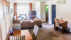 A compact living space with a sofa, dining table, and a kitchenette. - Harvest Lodge (Havelock North)