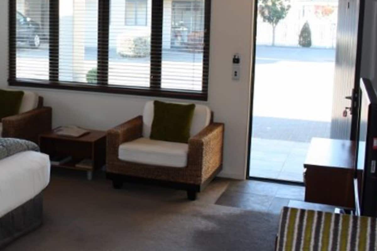 A hotel room with a large bed, two armchairs, a small table, and a TV.