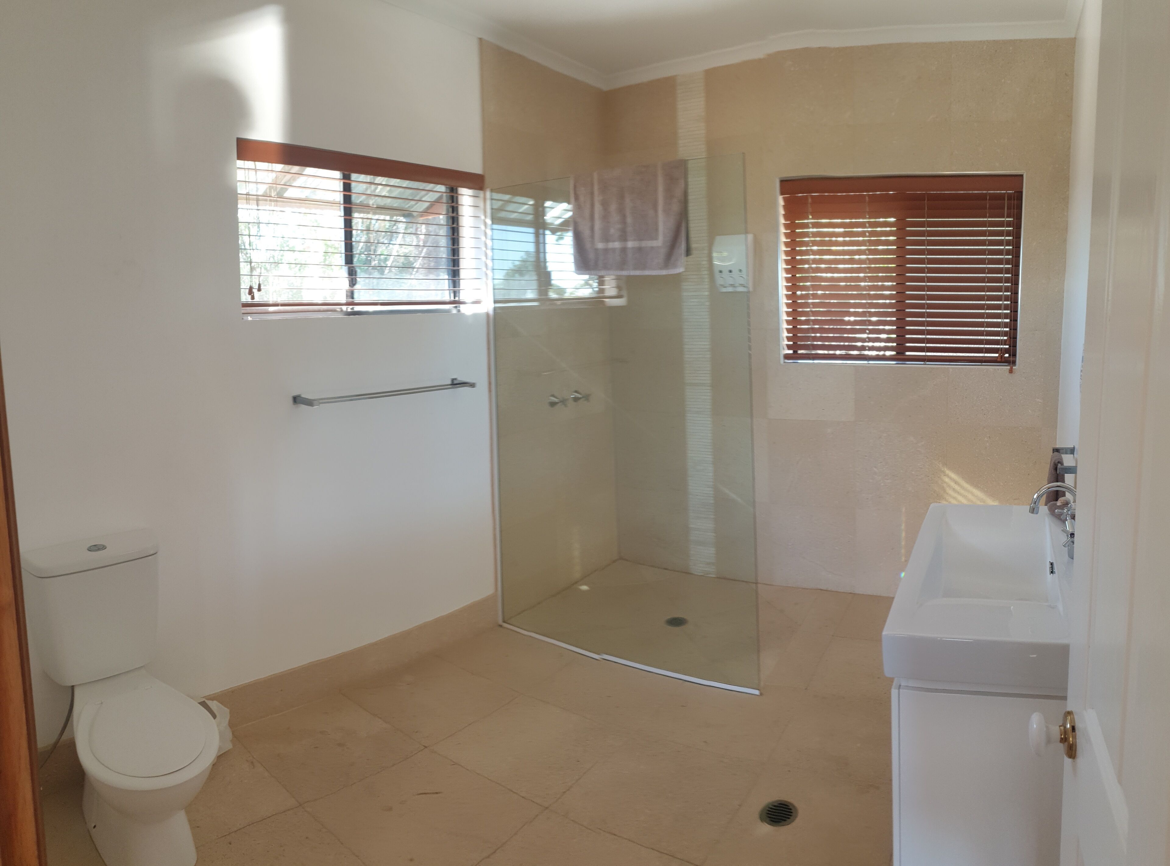 A bathroom with a glass shower enclosure, a toilet, and a sink.