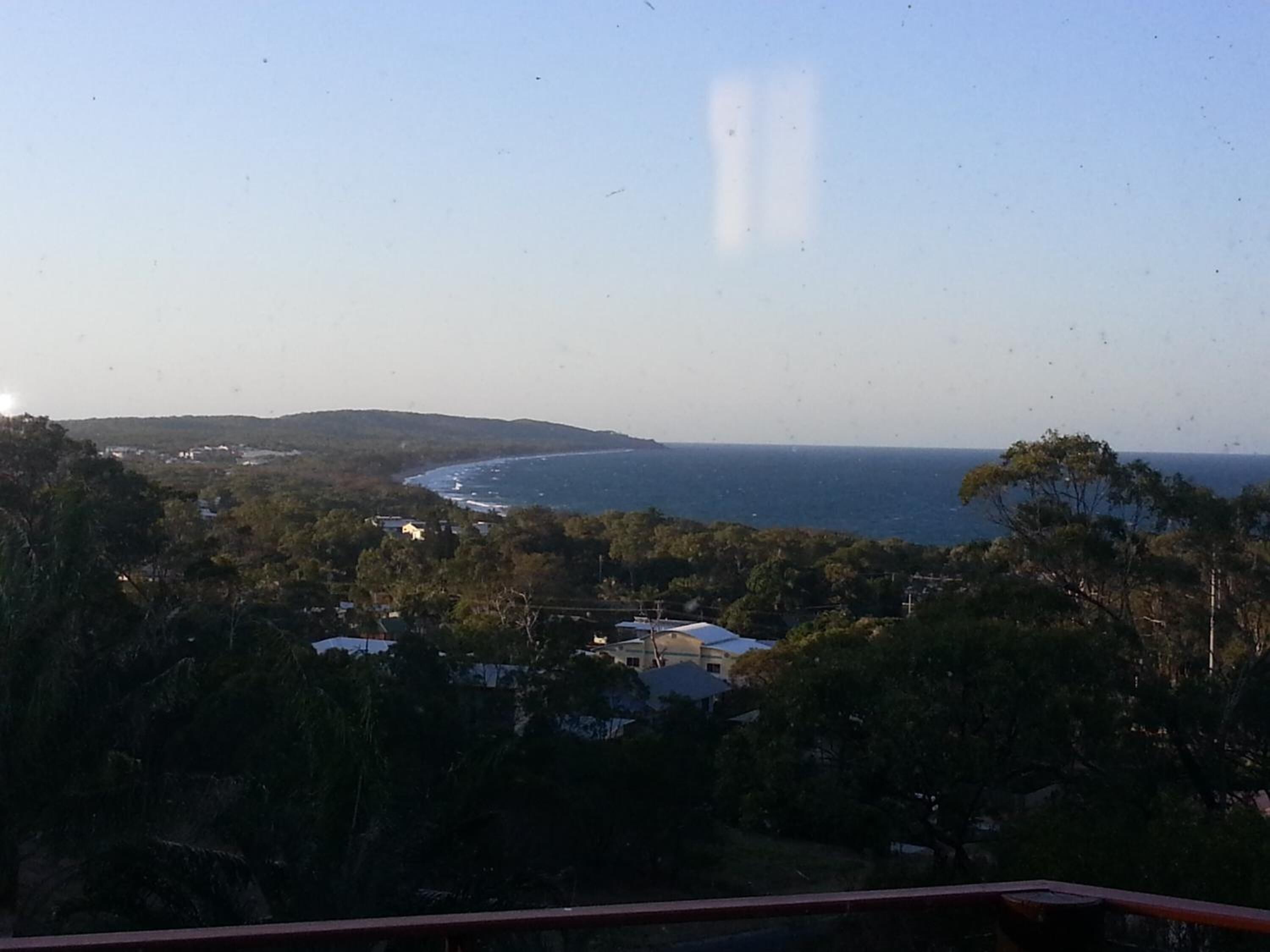 A coastal landscape with a view of the sea, surrounded by trees and a few buildings.