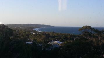 A coastal landscape with a view of the sea, surrounded by trees and a few buildings.