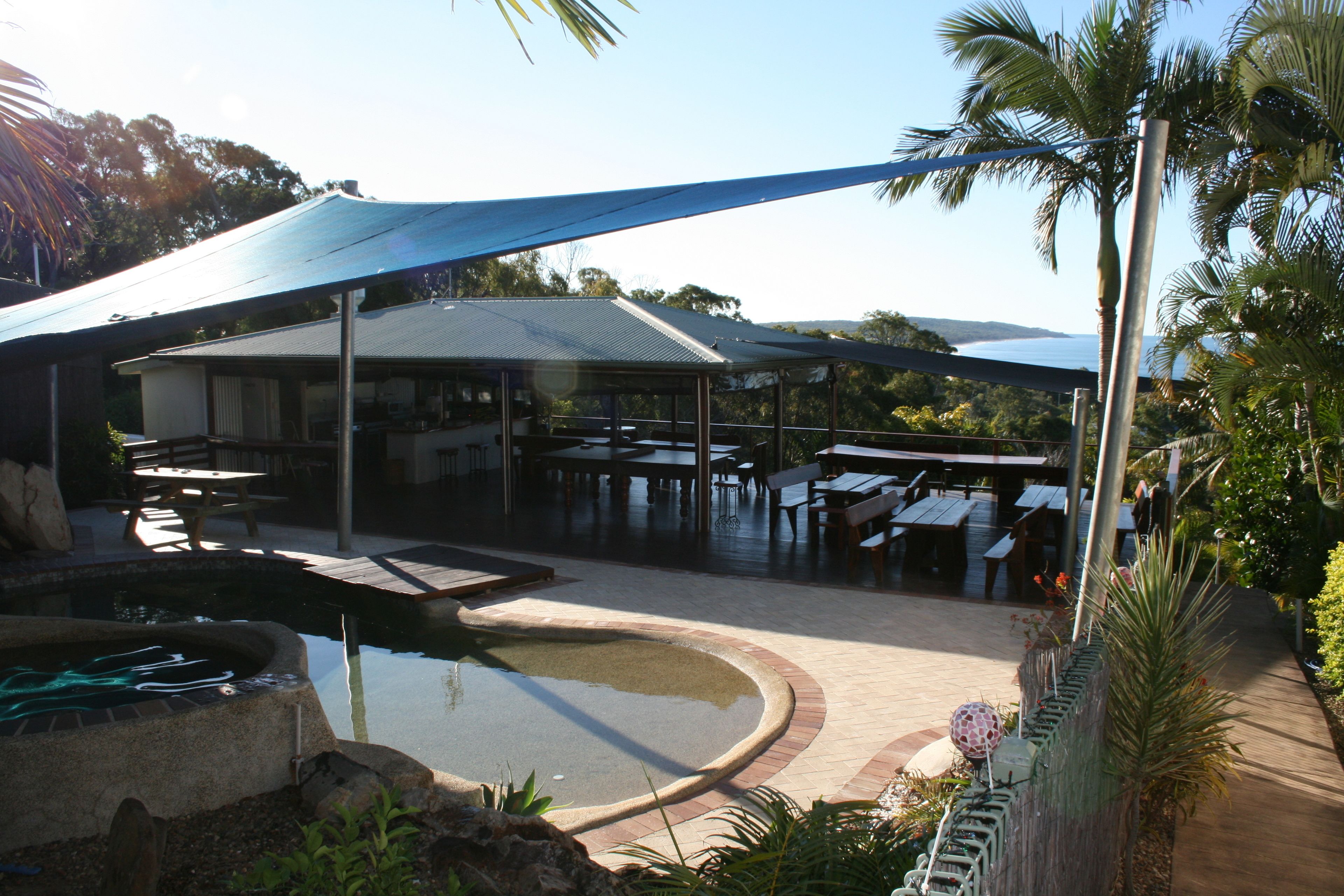 A covered outdoor area with tables and a swimming pool.