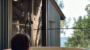 A person relaxing in a bathtub with a view of a tree and a building. - Treetops Seaview Montville (Montville)