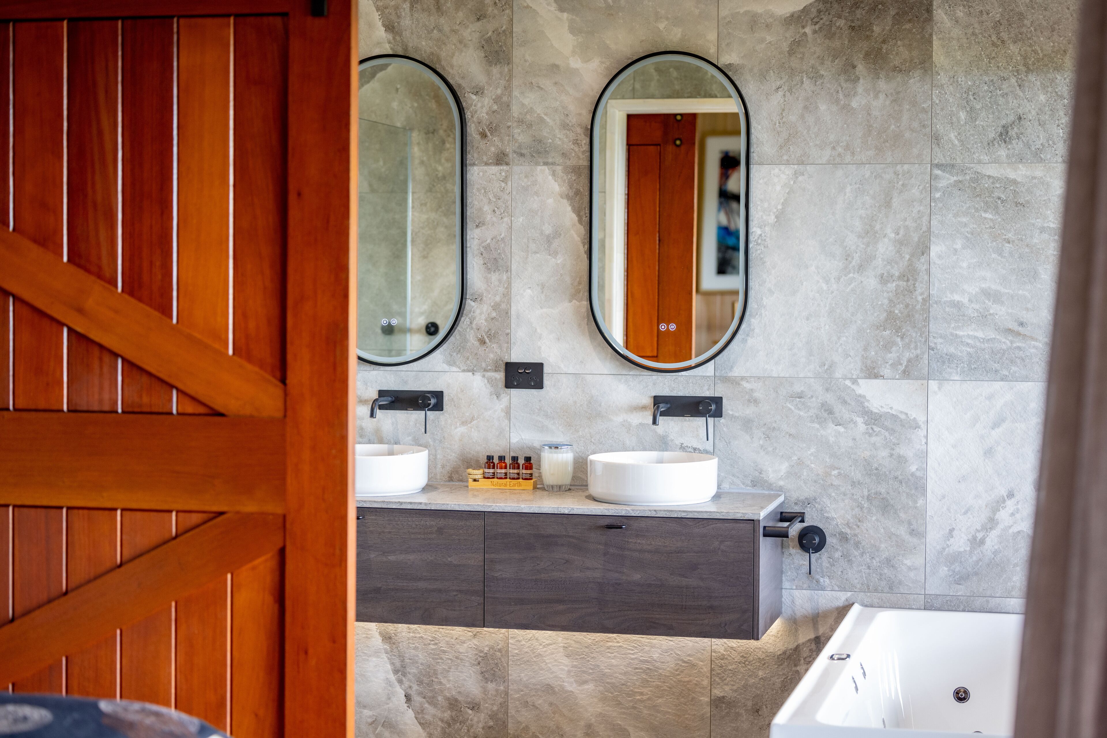 A bathroom with two sinks, a mirror, and a wooden door.