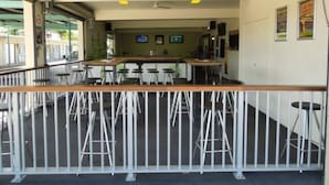 A bar area with stools and a counter, a ceiling fan, and a view of the outside. - Oonoonba Hotel Motel (Oonoonba)