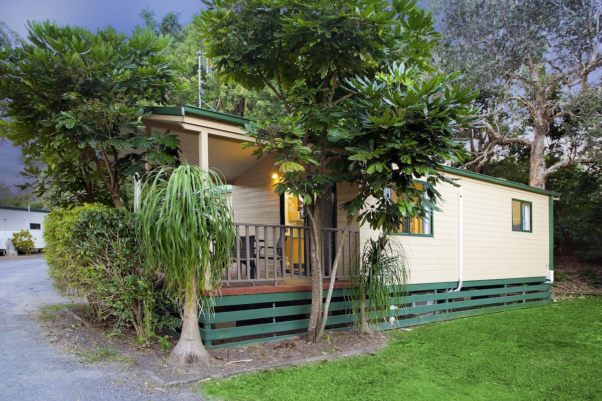 A small, single-story mobile home with a porch and a covered outdoor seating area.