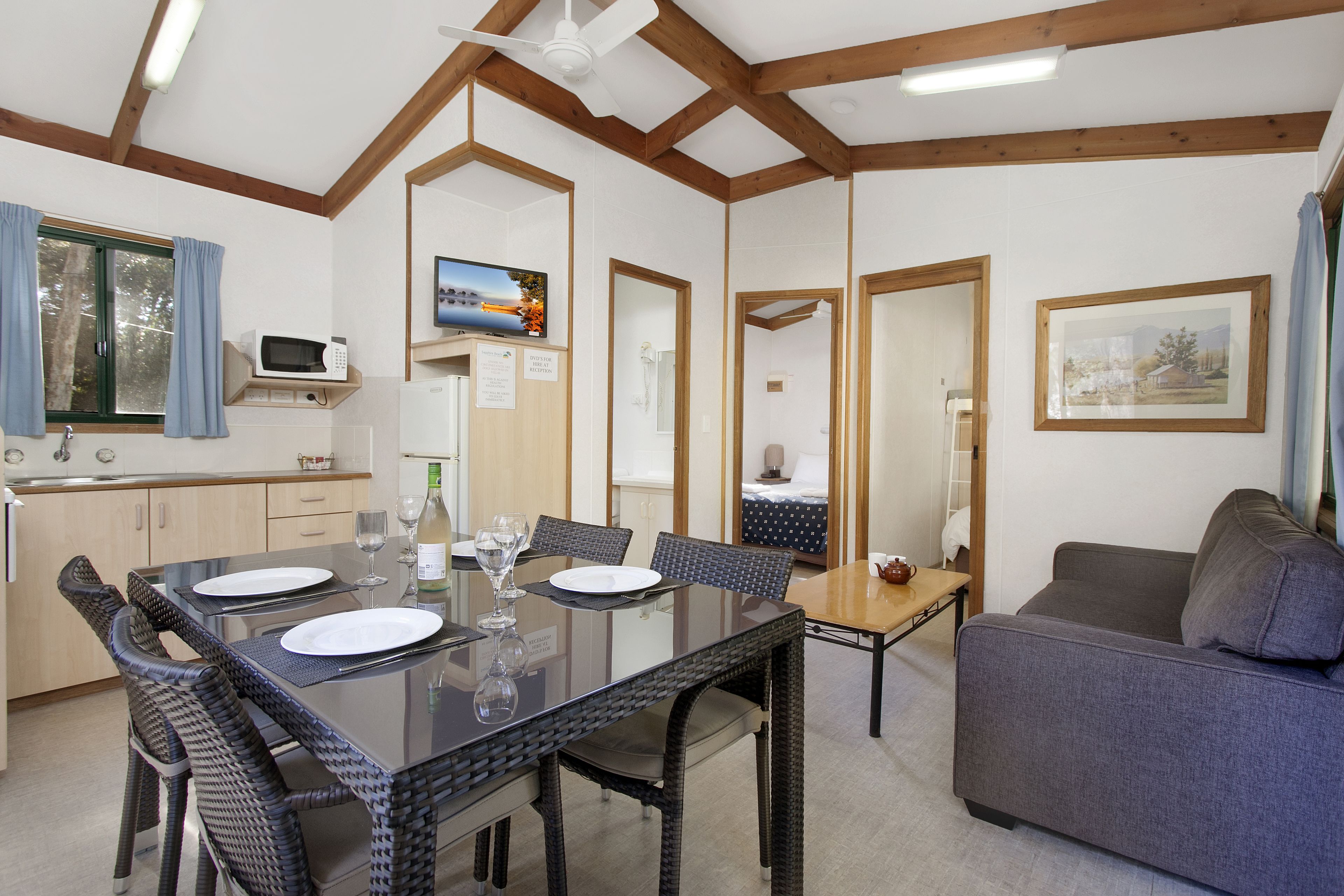 A modern kitchen with a dining area, a sofa, and a TV.