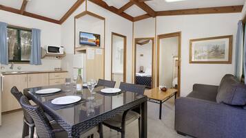 A modern kitchen with a dining area, a sofa, and a TV.