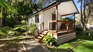 Una casa pequeña de un solo piso con un porche y una escalera que lleva a una terraza.