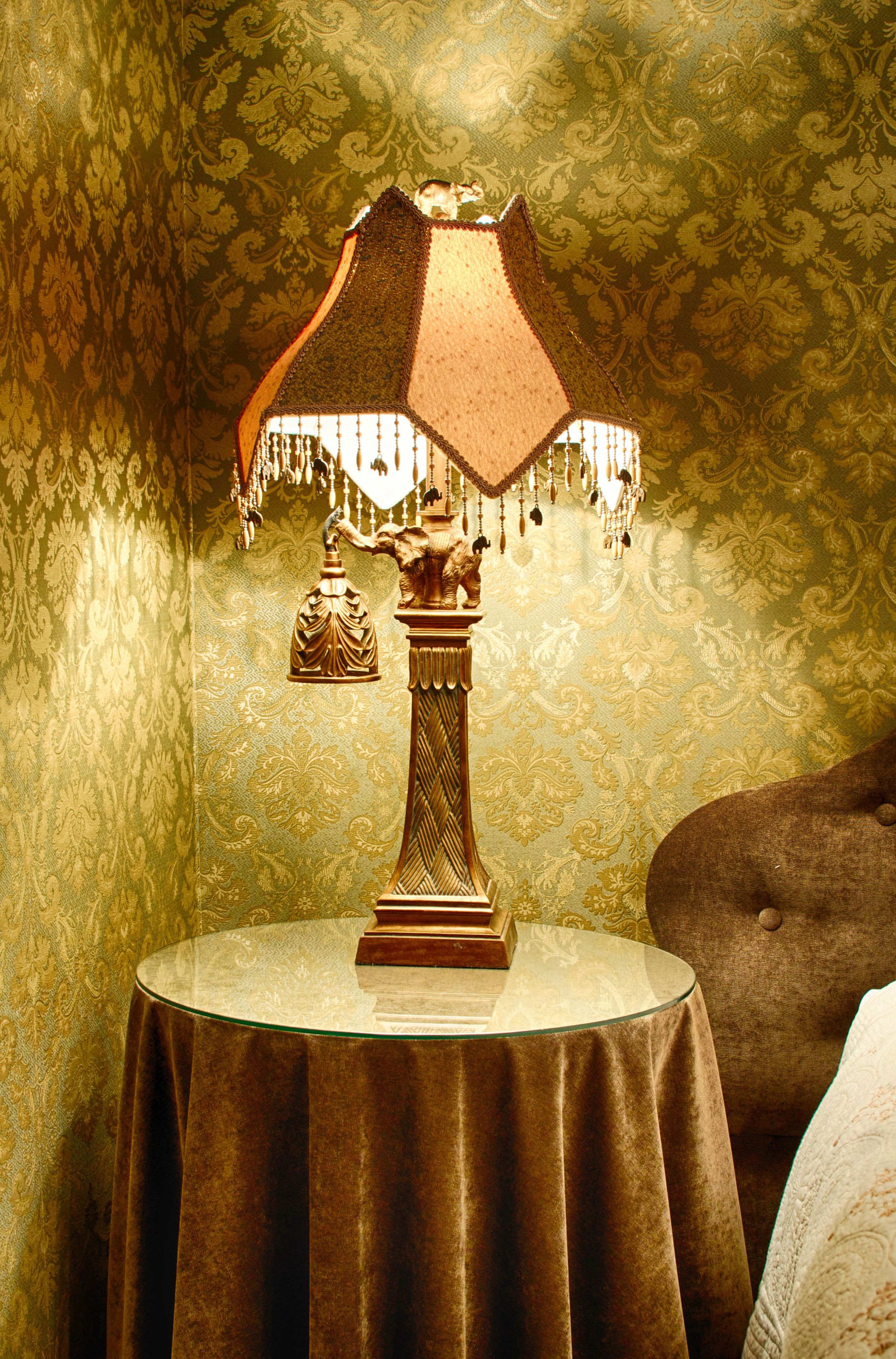 A table with a decorative lamp and a small statue on top.