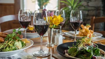 Una mesa de comedor con platos de comida, copas de vino y un salero.