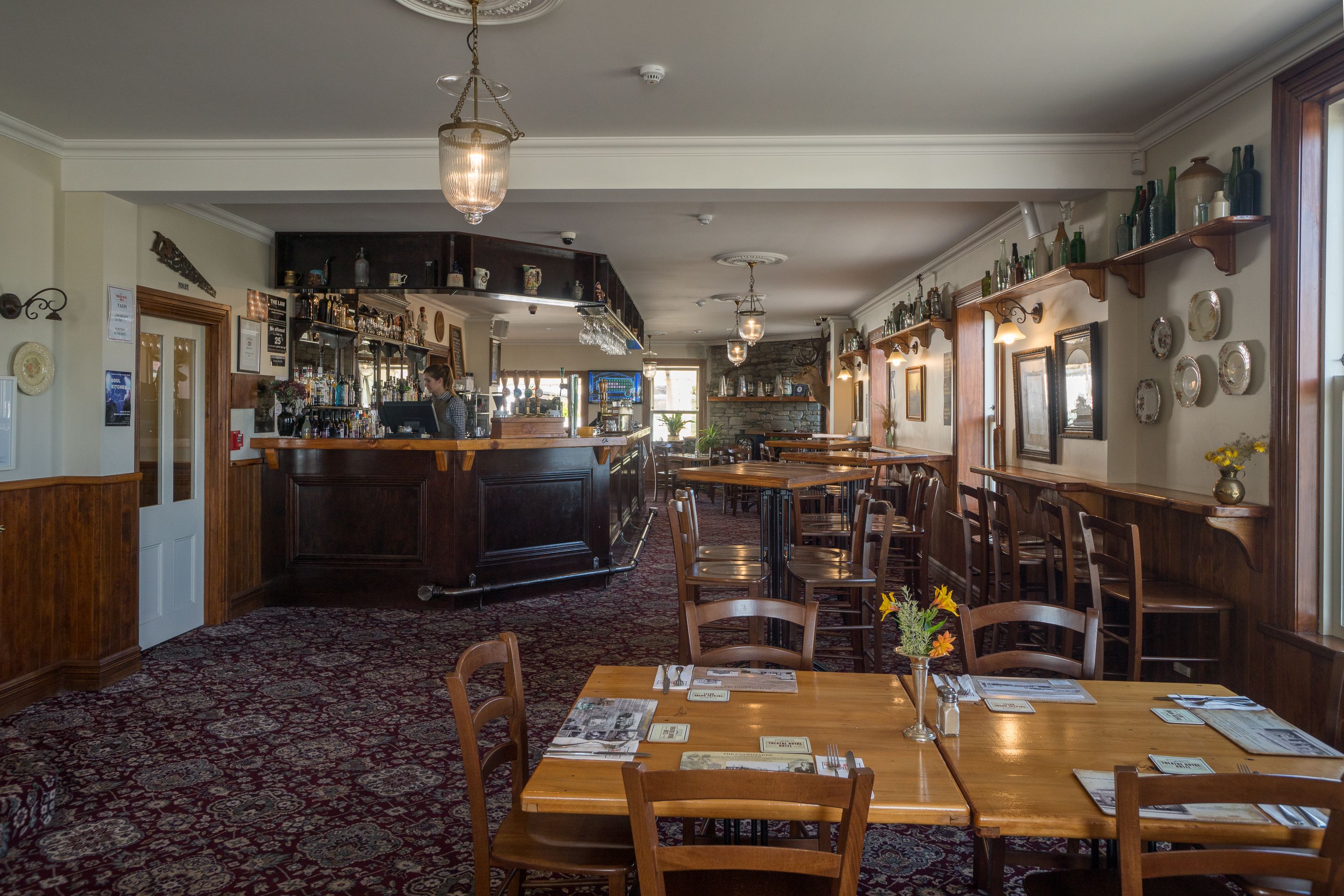 Een restaurant met houten tafels, stoelen en een bar.