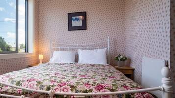 A room with a bed, a nightstand, a lamp, and a framed picture on the wall.