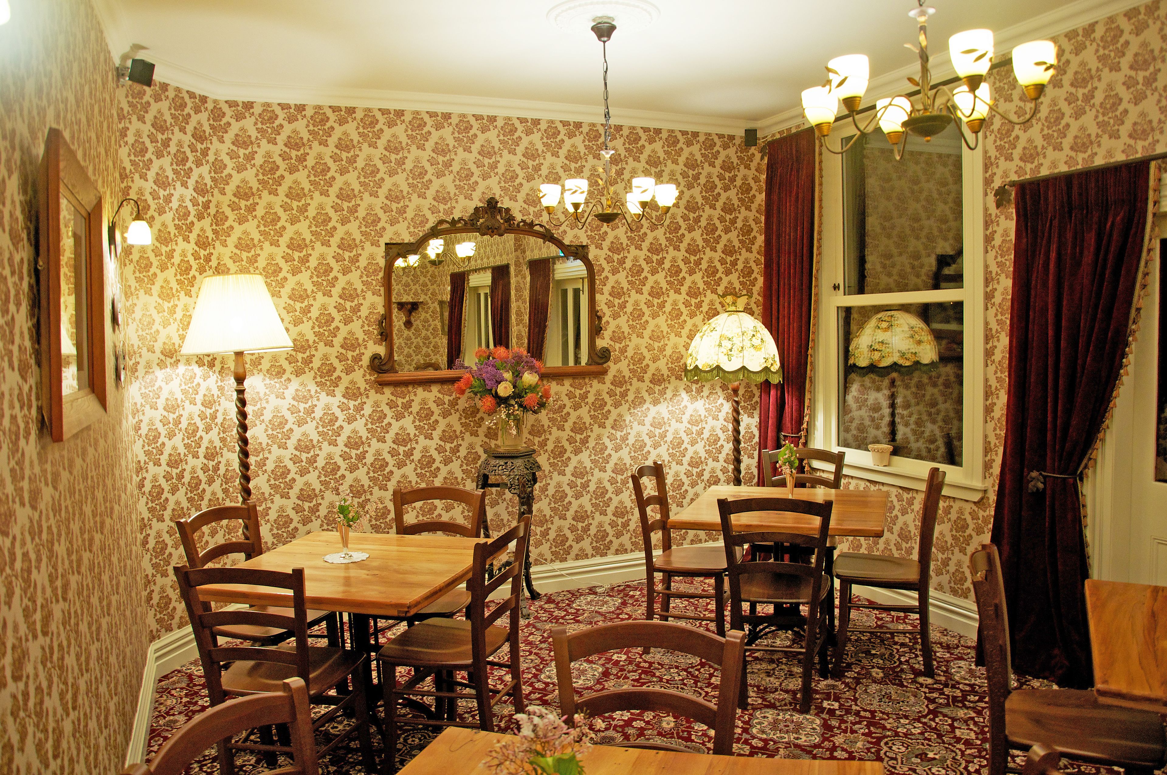 Une salle à manger avec une table et des chaises en bois, un lustre et des compositions florales.