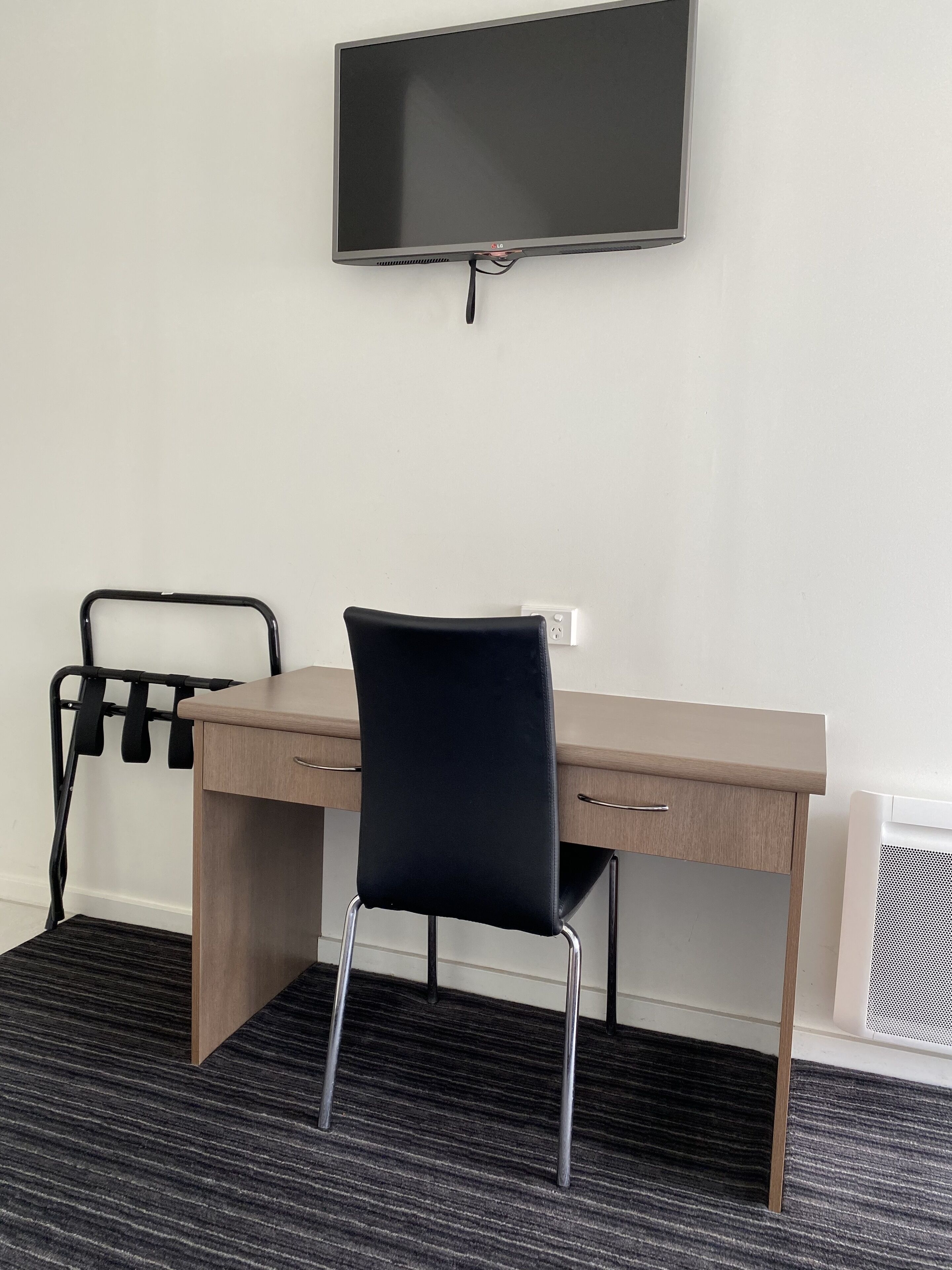 A modern office space with a desk, chair, and a mounted flat-screen TV.