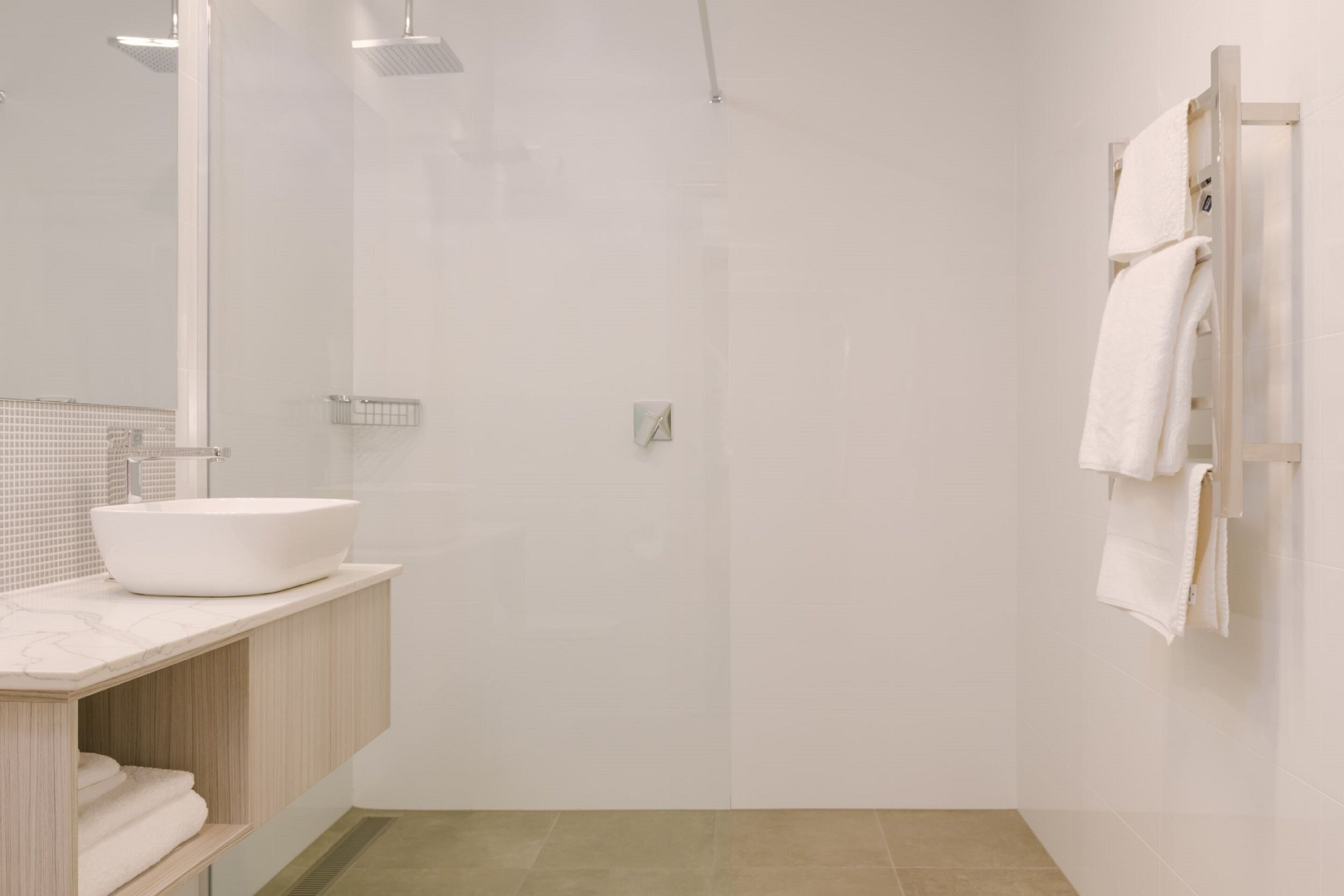 Een moderne badkamer met een grote spiegel, een witte wastafel en een douchehoek.