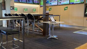 A hotel lobby with multiple seating areas, a reception desk, and several digital screens displaying sports content.