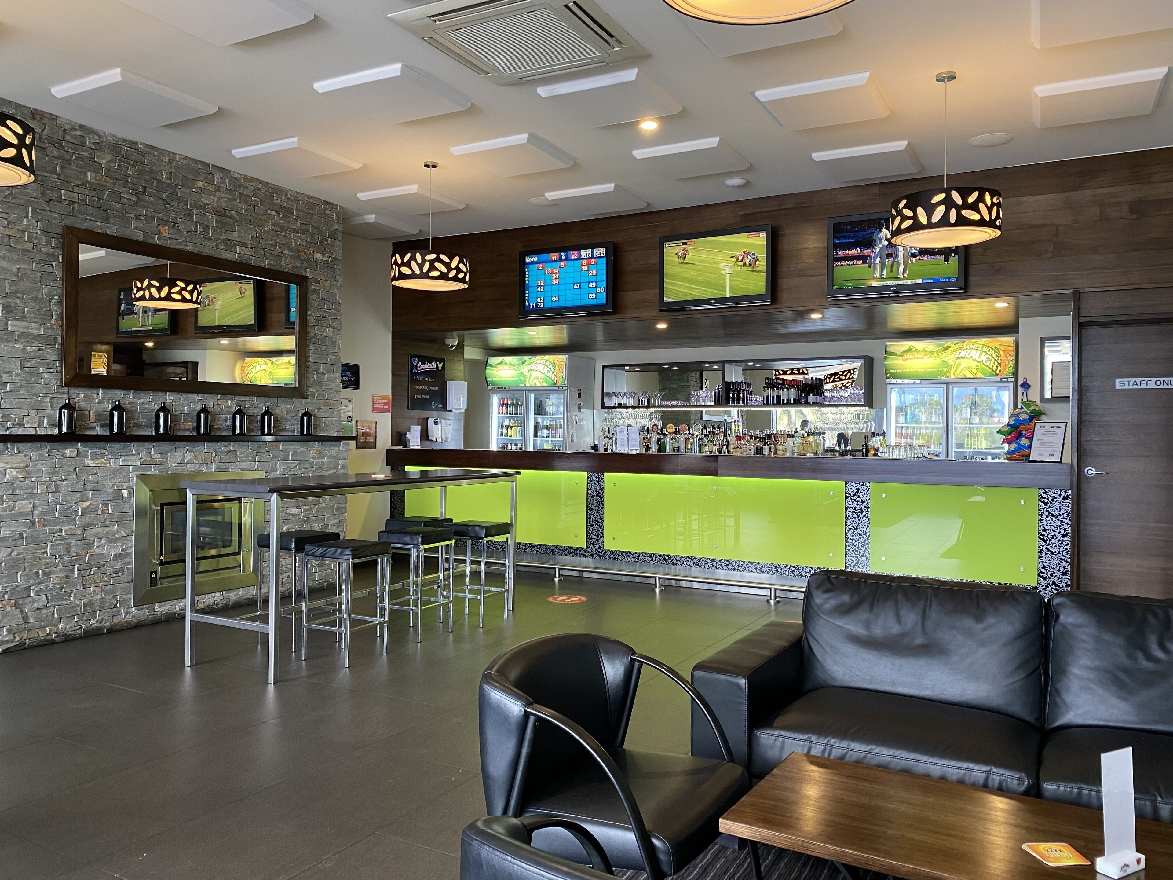 Uma área de bar moderna com balcão, várias telas e assentos.