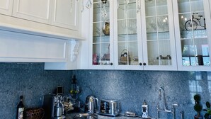 Una cocina con armarios blancos, encimera de mármol y una araña.