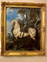 A portrait of a man in armor on horseback, framed in an ornate gold frame.
