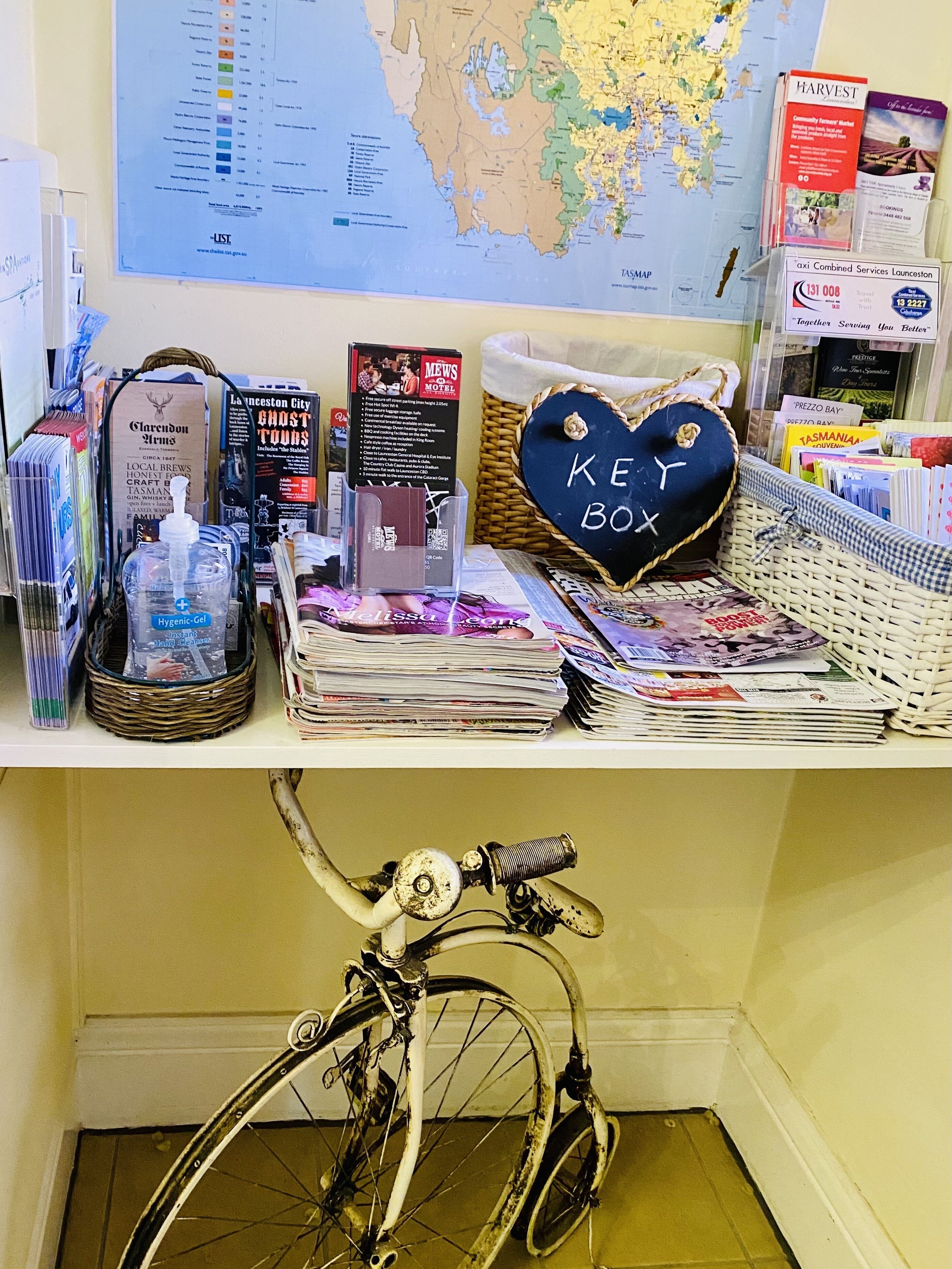 A desk with a map, a heart-shaped box labeled "KEY BOX", and various items including a bicycle.