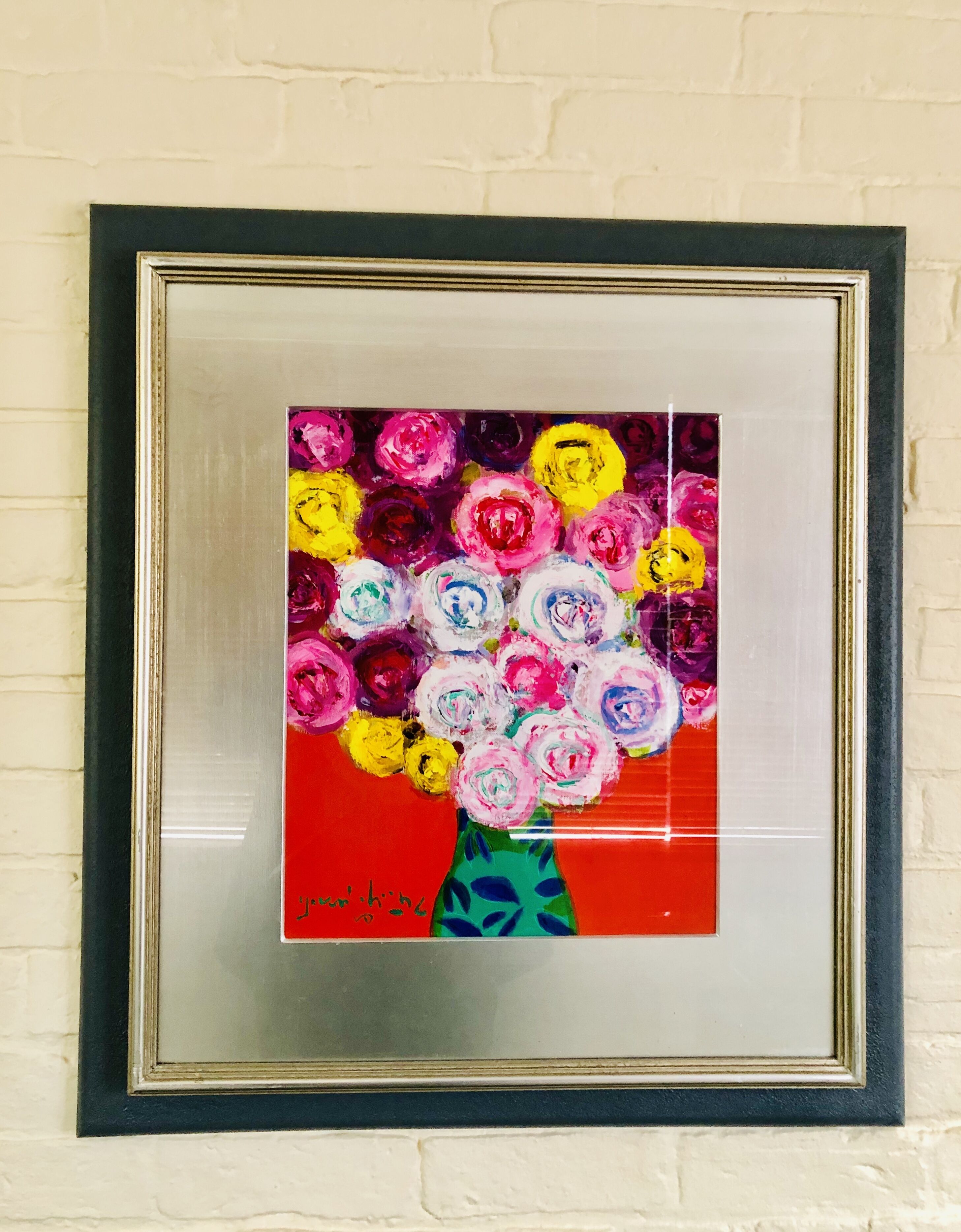 Une œuvre d’art encadrée représentant un arrangement floral aux couleurs vives, accrochée à un mur.