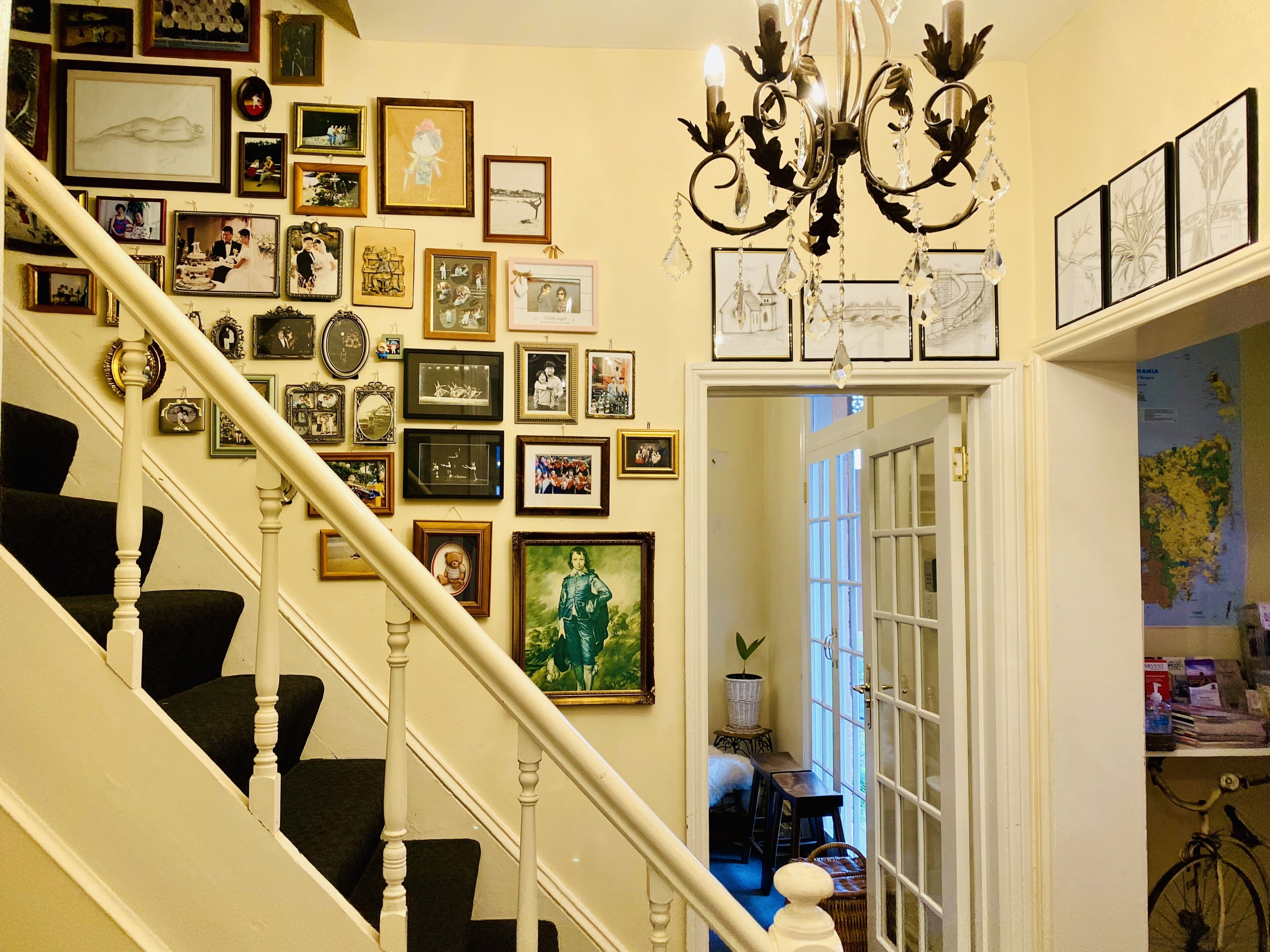 A staircase with a white railing and a wall adorned with numerous framed photographs and artwork.