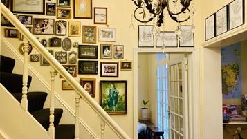 Una escalera con barandilla blanca y una pared decorada con numerosas fotografías y obras de arte enmarcadas.