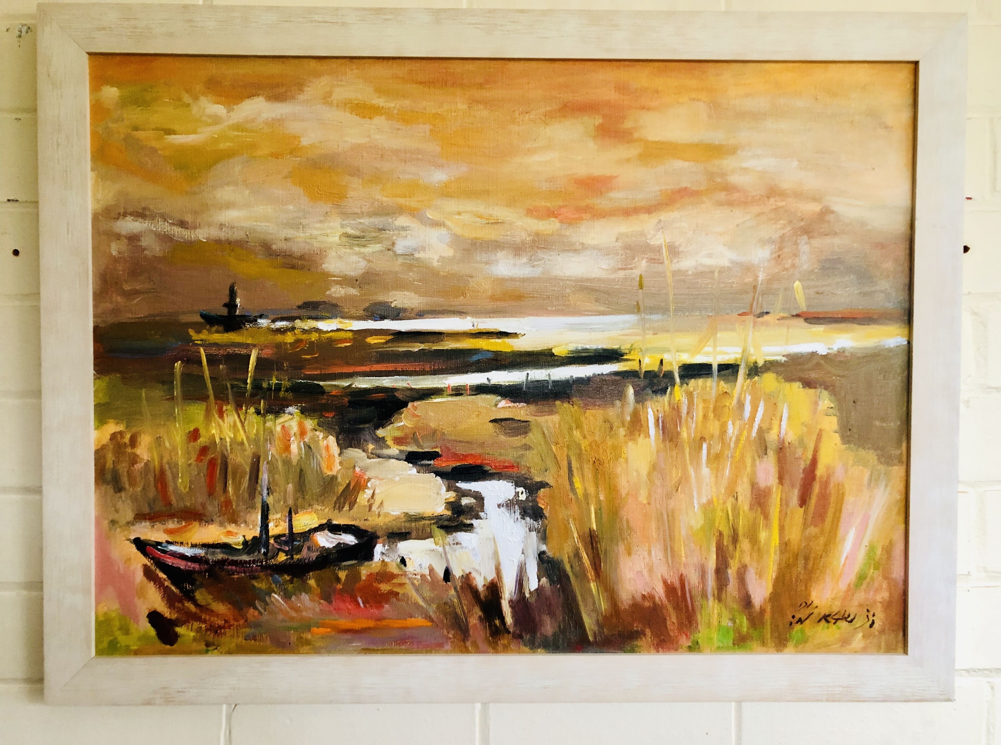 A framed painting of a landscape with a body of water, grass, and a distant boat.