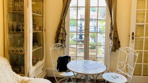 Una habitación con una mesa y sillas de comedor, un aparador con cristalería y vistas a un jardín por la ventana.