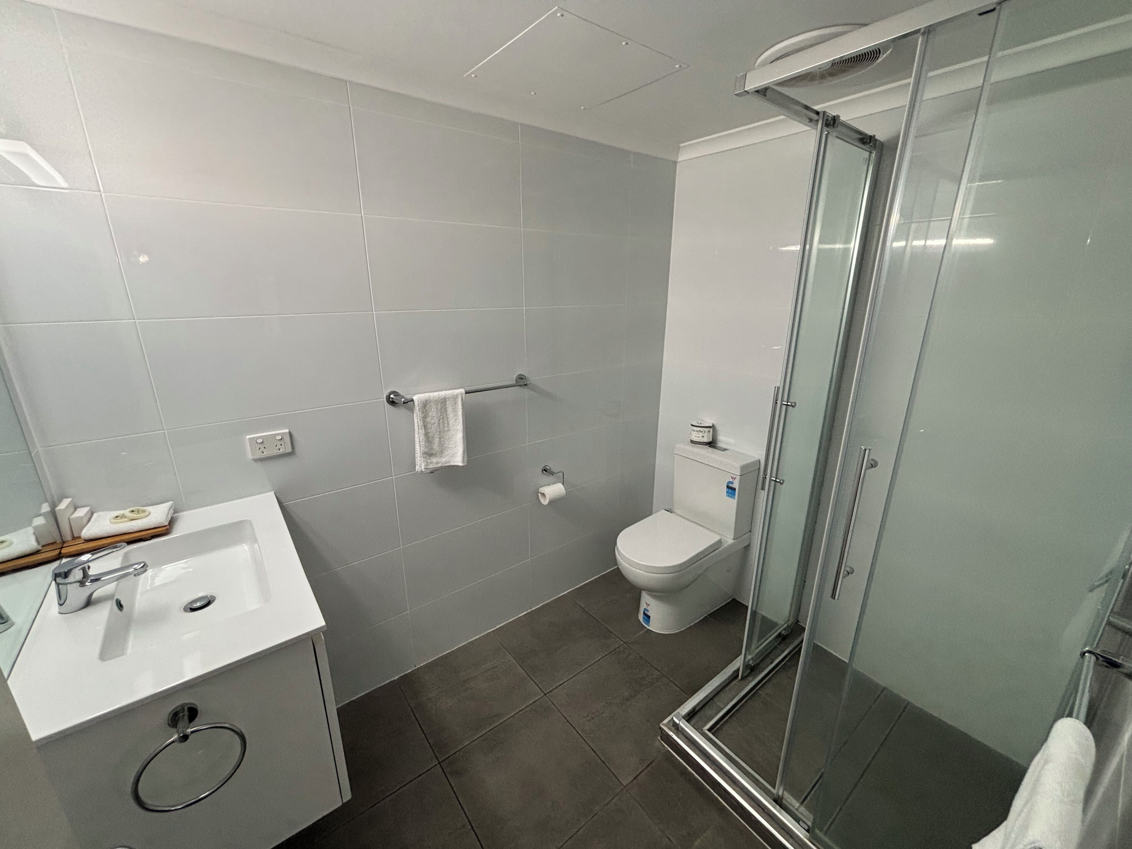 A modern bathroom with a glass shower enclosure, a white sink, and a toilet.
