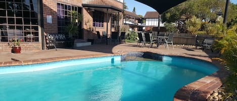 Una piscina al aire libre, sillones reclinables de piscina