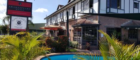 A pool area with a sign for the Shakespeare Motel and a restaurant named Romeo & Juliet's.